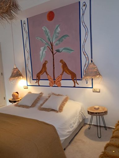 Chambre avec un mur décoré de lions et de palmiers, lit avec couvre-lit beige.